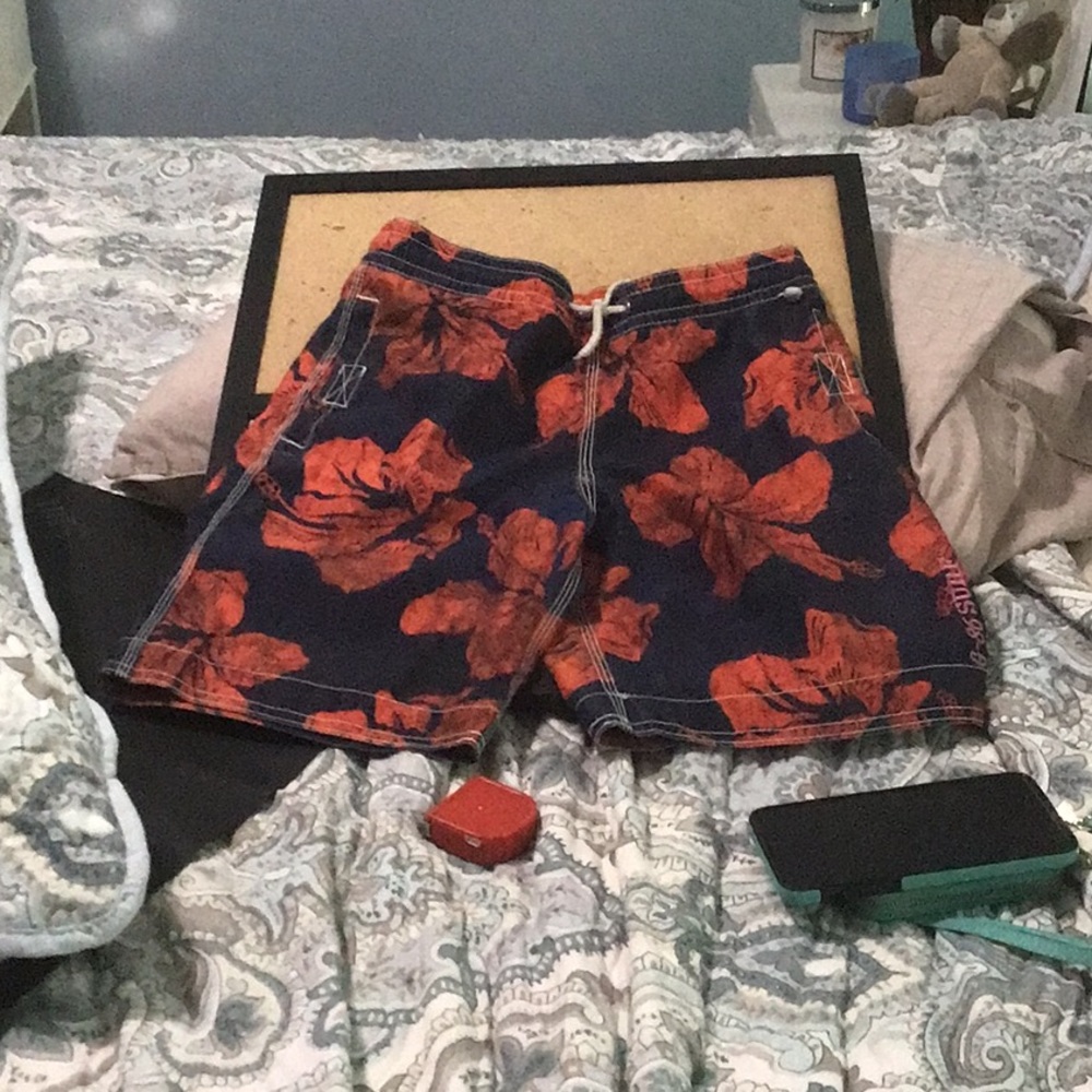 Kids swim shorts with 8” inseam, vibrant orange flowers on a blue background.